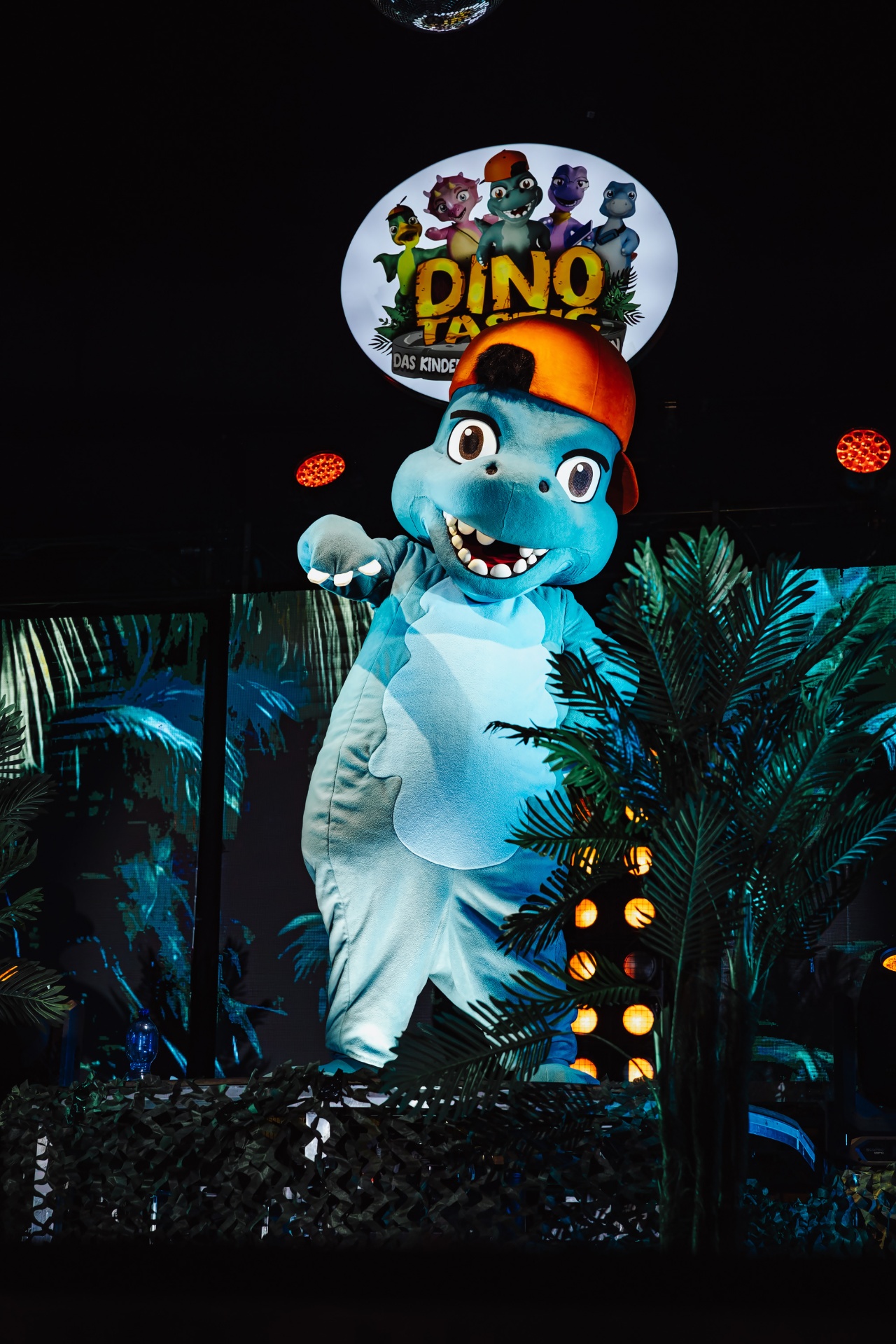 Dinotastic – blauer Dino-Charakter unter dem Showlogo auf der Bühne